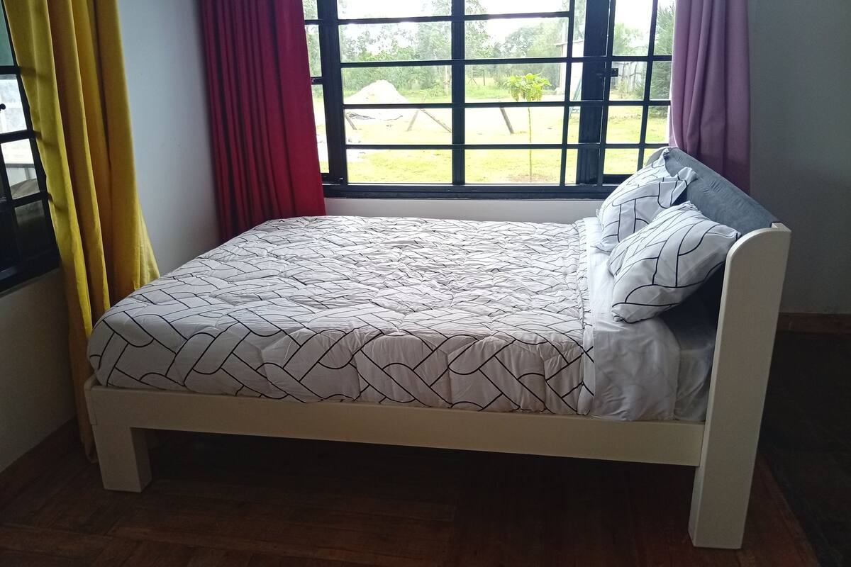 A bed with a geometric patterned bedspread, a headboard, and two pillows.
