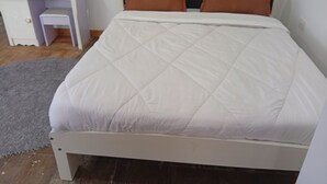 A bed with a white quilt, a wooden headboard, and two brown pillows. - Le Tai Village Homestay (Mweiga)