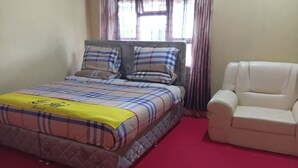 A bed with a plaid bedspread and pillows, a yellow blanket, and a red carpet. - Le Tai Village Homestay (Mweiga)