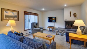 A living room with a sofa, armchair, coffee table, and fireplace. - Ski, Soak & Chill! Pool-View Winter Park Condo (Winter Park)