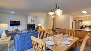A dining area with a wooden table set for four, surrounded by wooden chairs. - Ski, Soak & Chill! Pool-View Winter Park Condo (Winter Park)