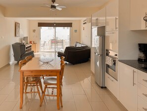 Una cocina moderna con refrigerador, horno y comedor con sillas y una mesa.