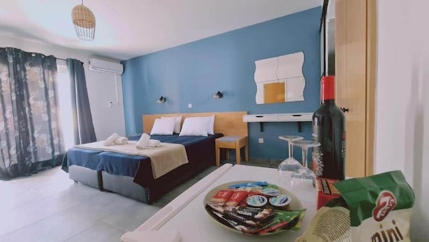 Une chambre d’hôtel avec un lit, une petite table avec des en-cas, une bouteille de vin et un minibar.