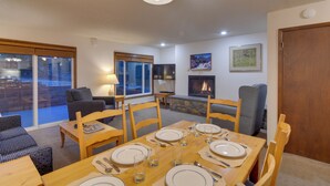A dining area with a table set for four, surrounded by chairs, a fireplace, and a television. - Shuttle to Winter Park Resort! Group Condo w/ Pool (Winter Park)
