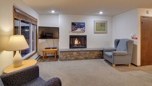 A cozy living room with a fireplace, a television, and comfortable seating. - Shuttle to Winter Park Resort! Group Condo w/ Pool (Winter Park)