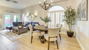 A dining area with a round wooden table, six upholstered chairs, a chandelier, and a potted plant. - < 1 Mi to Golf: Charming Ahwatukee Foothills Villa (Phoenix)