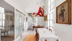 A dining area with a long table, chairs, a staircase, and a painting on the wall. - Spacious, bright apartment (Oberursel / Taunus)