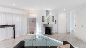 A modern living room with a glass coffee table, a sofa, a fireplace, and a staircase leading to another level. - Spacious, bright apartment (Oberursel / Taunus)