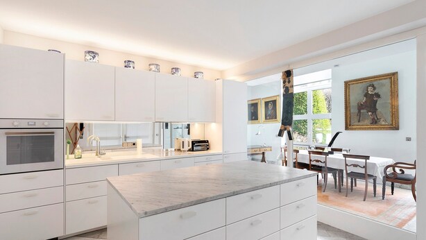 A modern kitchen with white cabinetry, a marble countertop, and a dining area with a table and chairs. - Spacious, bright apartment (Oberursel / Taunus)