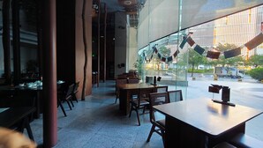 A modern restaurant interior with a long dining area, high ceilings, and large windows offering a view of the street and buildings outside. - Paxin·High-Altitude City View Apartment (Canton Fair Complex Pazhou Subway Station Branch) (Guangzhou)