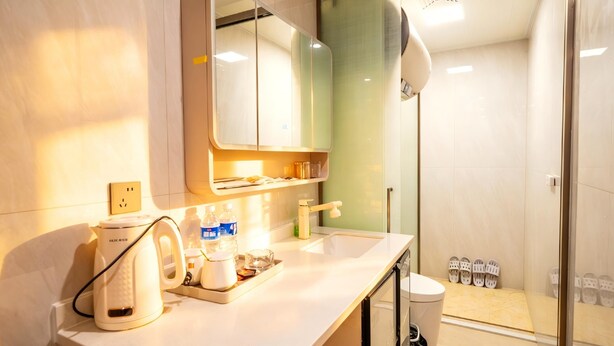 A modern bathroom with a shower, a sink with a kettle, and a mirror. - Paxin·High-Altitude City View Apartment (Canton Fair Complex Pazhou Subway Station Branch) (Guangzhou)