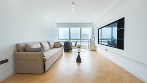 A modern living room with a sofa, a coffee table, and a large window with a view of a cityscape. - Paxin·High-Altitude City View Apartment (Canton Fair Complex Pazhou Subway Station Branch) (Guangzhou)