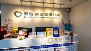 A reception desk with a sign for Paxiin High-Altitude City View Apartment. - Paxin·High-Altitude City View Apartment (Canton Fair Complex Pazhou Subway Station Branch) (Guangzhou)