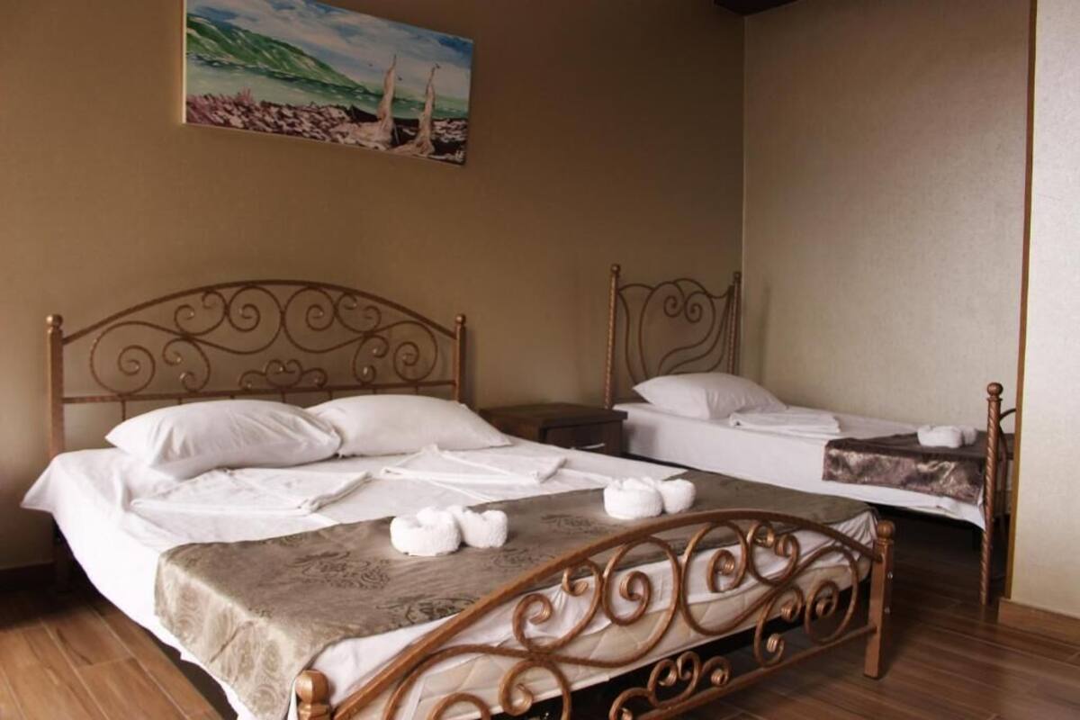 A double room with two beds, each with a headboard, a painting on the wall, and a wooden floor.