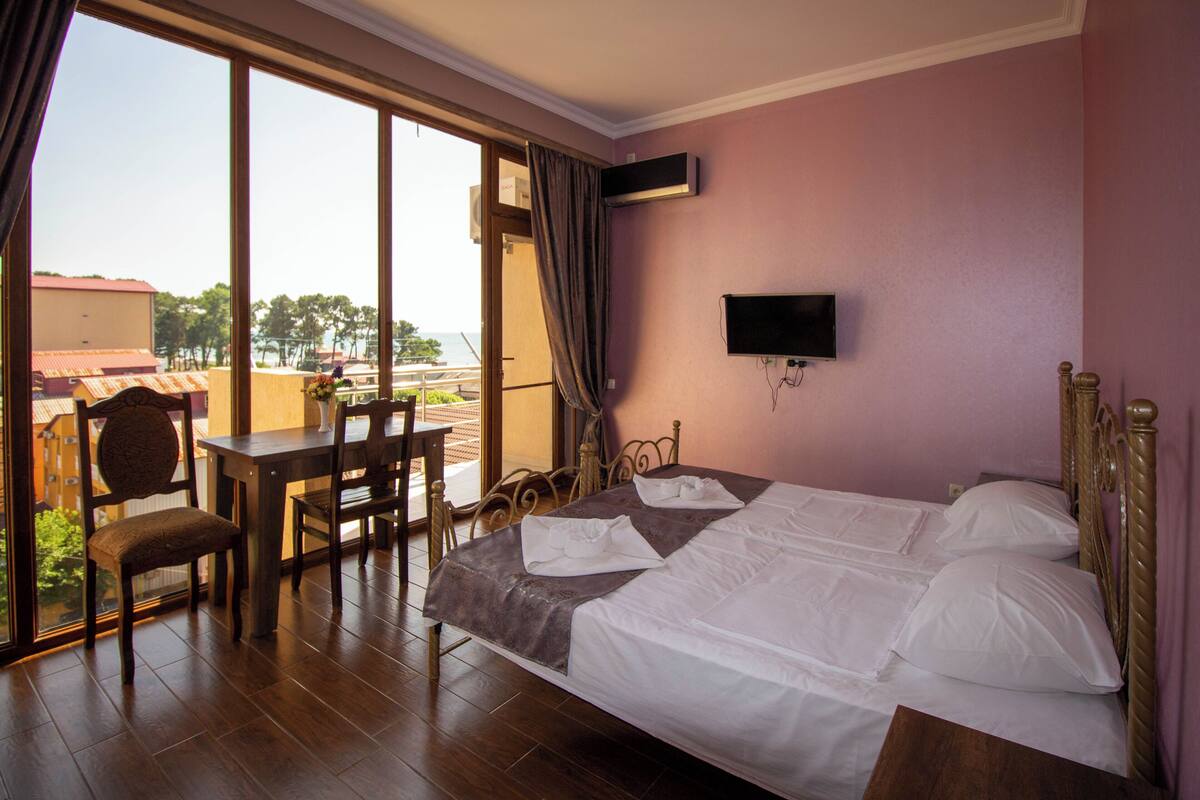 A hotel room with a bed, a desk, a chair, and a TV.