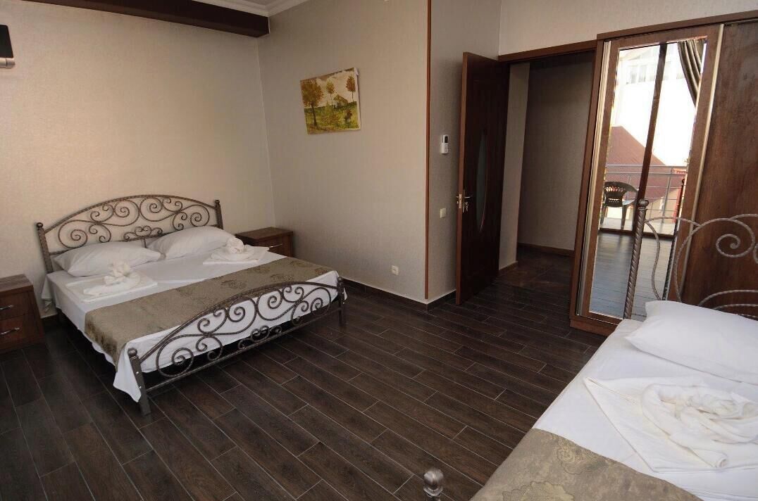 A bedroom with a metal bed frame, a wooden floor, a sliding door, and a small bedside table.