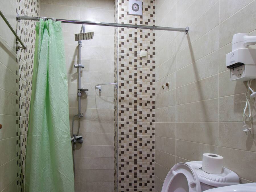 Un baño con ducha, inodoro y un secador de pelo en la pared.