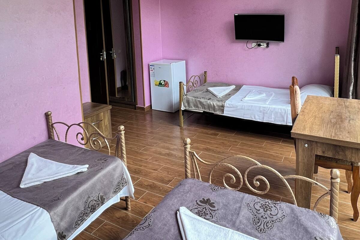 A room with two beds, a small table, a TV, and a refrigerator.