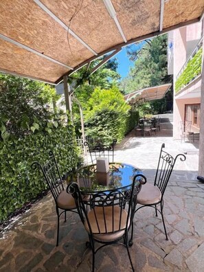 An outdoor patio with stone flooring, a glass-top table, and metal chairs.