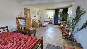 Een gezellige woonkamer met een bank, salontafel en een houten kast vol boeken.