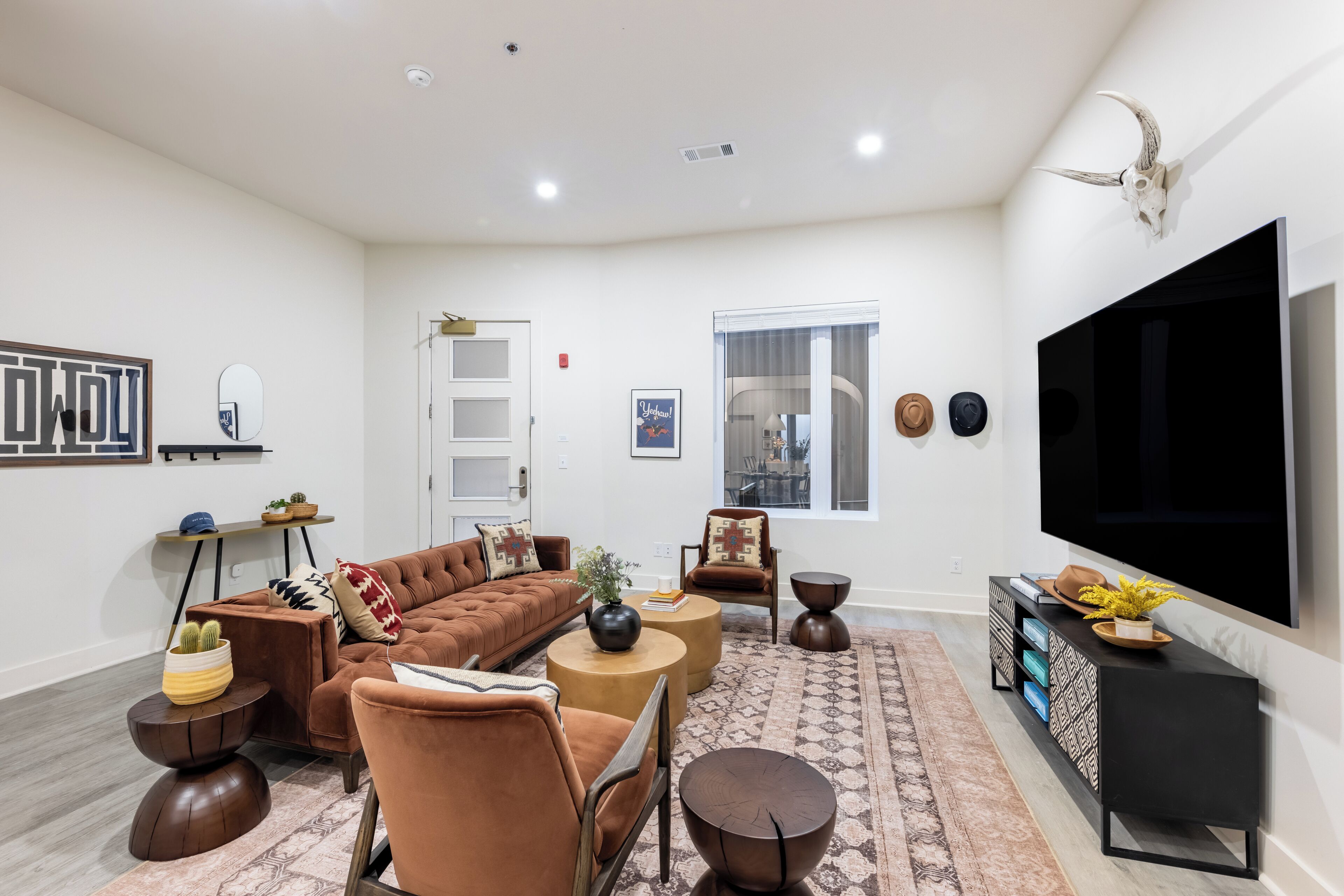Ein modernes Wohnzimmer mit einer Eckcouch, Sesseln, einem Couchtisch und einem an der Wand montierten Fernseher.