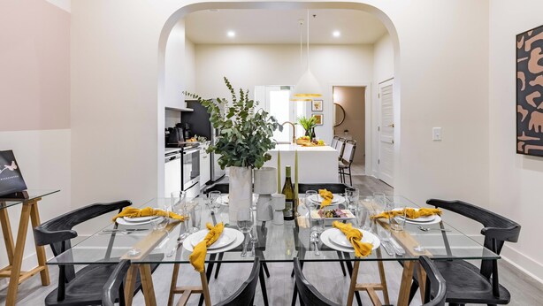 Un espace repas moderne avec une table en verre pouvant accueillir six personnes, entourée de chaises noires.