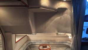 Ein kompakter, gut beleuchteter Innenraum mit einem kleinen Tisch und einer Bank, vermutlich Teil eines Fahrzeugs oder Gebäudes.