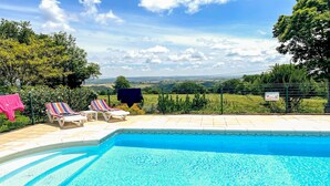 Ein Schwimmbecken mit Liegestühlen und Blick auf die Landschaft.