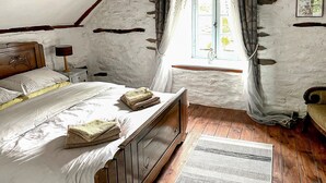 Ein rustikales Schlafzimmer mit einem hölzernen Bett, einem Nachttisch, einem Fenster mit Vorhängen und einem Holzboden.