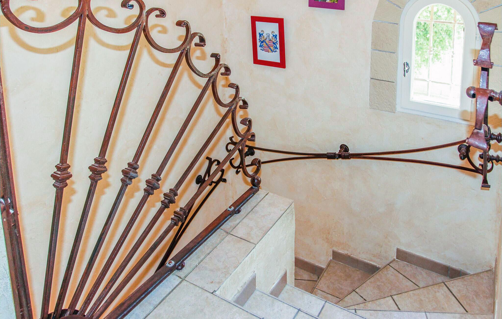 Un escalier orné de rampes en métal ouvragé et un petit tableau encadré accroché au mur.