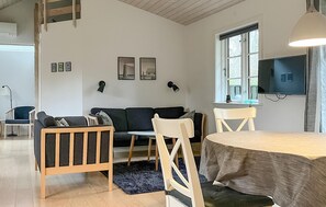 Ein Wohnzimmer mit einer Couch, Sesseln, einem Tisch und einem Fernseher.
