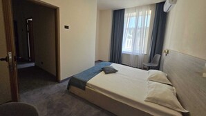 Een hotelkamer met een bed, een stoel, een douche en een raam met gordijnen.