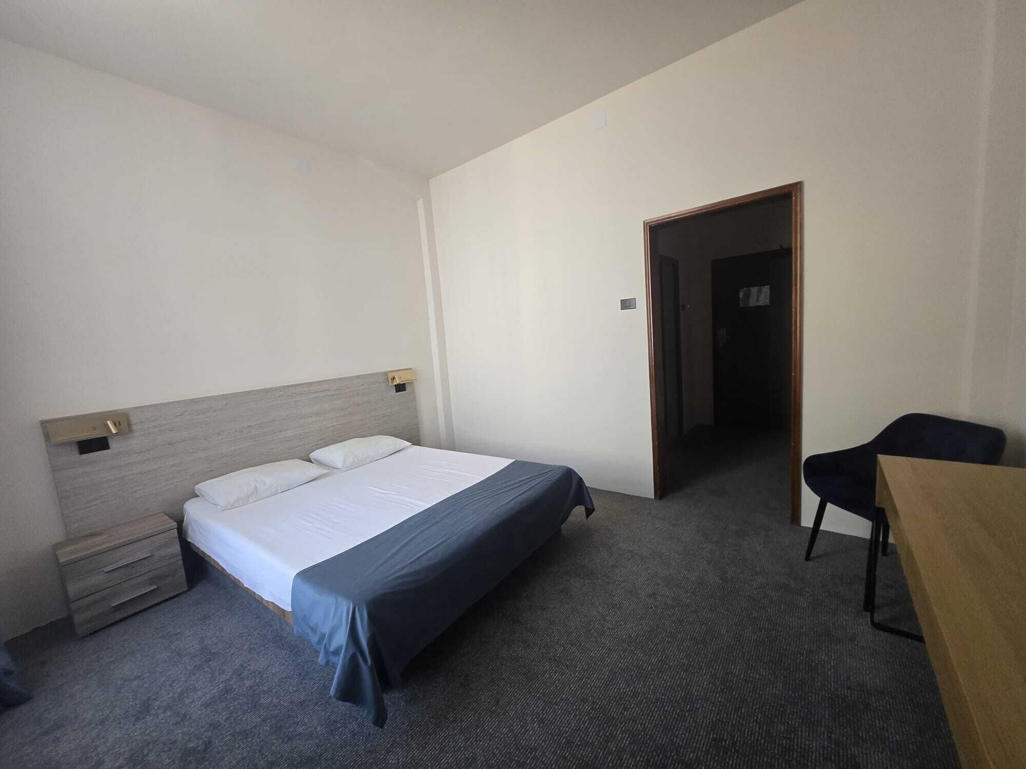 A hotel room with a bed, a desk, and a chair.