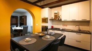 A modern kitchen with white cabinets, a black countertop, and a dining area with a table set for two. - Amazing home in Cividale del Friuli (Cividale del Friuli)