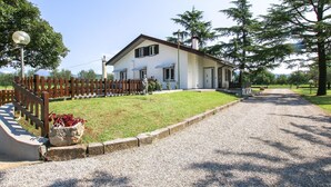 A two-story house with a gravel driveway, a wooden fence, and a statue in the front yard. - Amazing home in Cividale del Friuli (Cividale del Friuli)