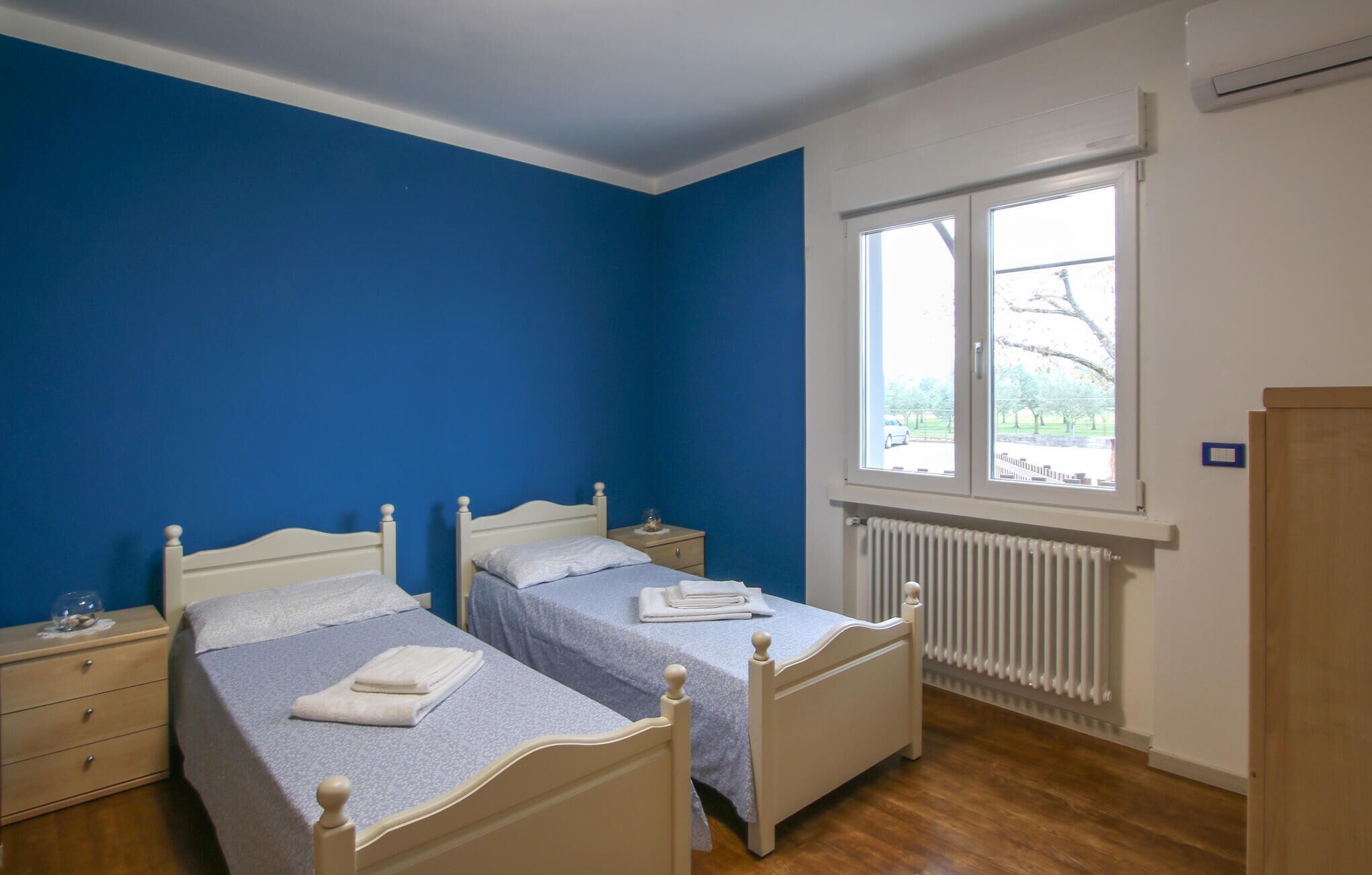 Une chambre avec deux lits, une fenêtre et un radiateur.