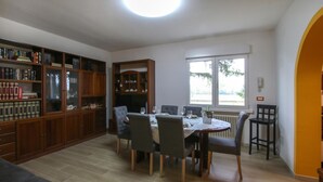 A dining area with a round table, chairs, and a bookshelf with books and decorative items. - Amazing home in Cividale del Friuli (Cividale del Friuli)