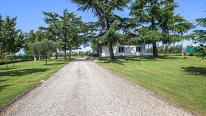 A gravel driveway leading to a white house with a red roof, surrounded by a grassy area and trees. - Amazing home in Cividale del Friuli (Cividale del Friuli)