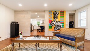 Un salon avec un jeu d’échecs, un canapé et un tableau abstrait aux couleurs vives.