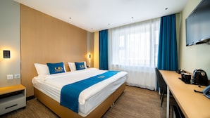 Ein Hotelzimmer mit Bett, Schreibtisch, Fernseher und einer Kaffeemaschine.
