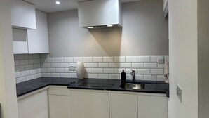 Een moderne keuken met witte kasten, een zwart aanrecht, een roestvrijstalen spoelbak en een geïntegreerde afzuigkap.