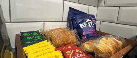 A tray with various packaged food items, including snacks and bread, in a kitchen setting with white tiled walls.