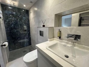 A modern bathroom with a glass-enclosed shower, a white sink, and a toilet. - Stylish studio with wet room & kitchen (London)