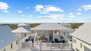 A coastal property with multiple buildings, a covered patio with outdoor furniture, and a view of the ocean. - Beach Sea-ker's Retreat by AvantStay | Rooftop Deck w/ Views, Pool, Luxury 5BDR (Inlet Beach)