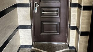 Una puerta marrón oscuro con teclado numérico, timbre y buzón.