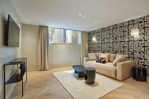 Un soggiorno moderno con un divano, un tavolino, una televisione e una parete decorata.