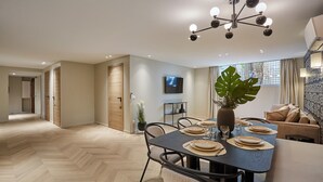 A modern dining area with a herringbone wood floor, a dark dining table set for four, and a large plant centerpiece. - Wonderful flat Luxembourg Park St Germain des près (Paris)
