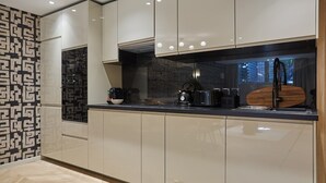 A modern kitchen with light-colored cabinets, a black countertop, and a patterned backsplash. - Wonderful flat Luxembourg Park St Germain des près (Paris)