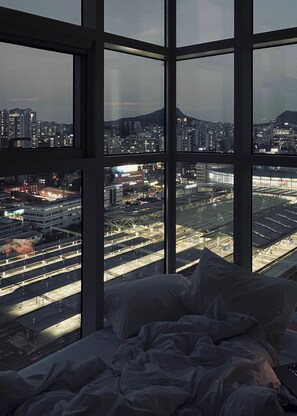 A bedroom with a large window overlooking a cityscape and a mountain. - [Seoul Station]Panorama Skyline  – Nice View & Free Gym (Seoul)