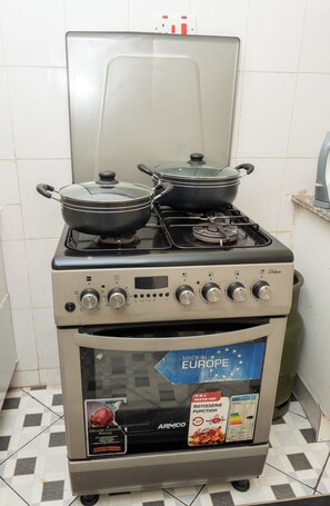 A kitchen with a stove, pots, and a range hood. - Tulia Homestays (Nakuru)